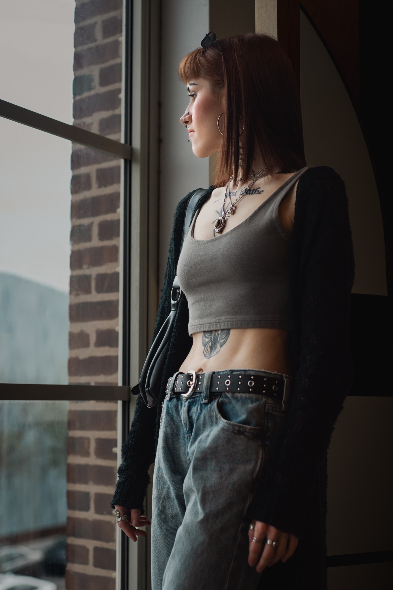 A woman looks through a tall window, framed by brick and daylight.